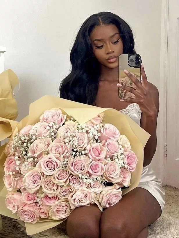 Femme noire avec un énorme bouquet de fleurs roses.