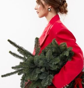 Femme blanche brune avec un costume rouge et un sapin