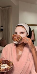 Femme noire avec un masque de beauté et buvant du thé.