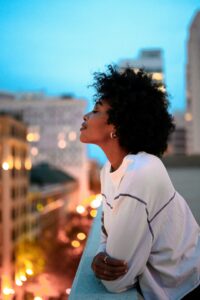 Femme noire aux cheveux afros en paix sur son balcon