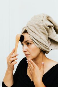 Femme blanche avec un linge sur les cheveux et une brosse sur le visage