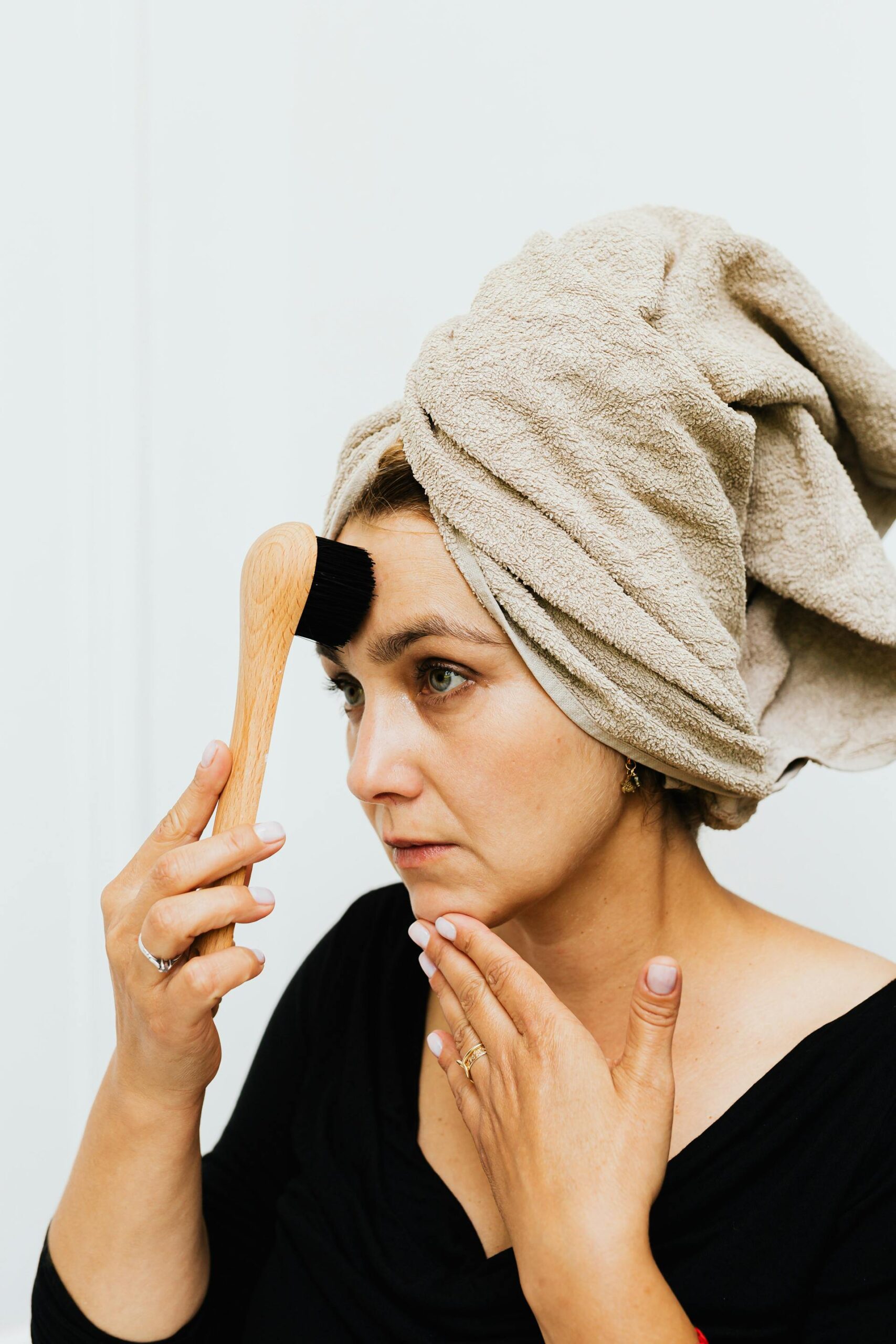 Femme blanche avec un linge sur les cheveux et une brosse sur le visage