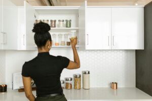 Femme noire qui range ses armoires de cuisine