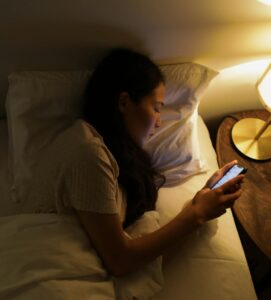 Femme asiatique dans son lit sur son téléphone