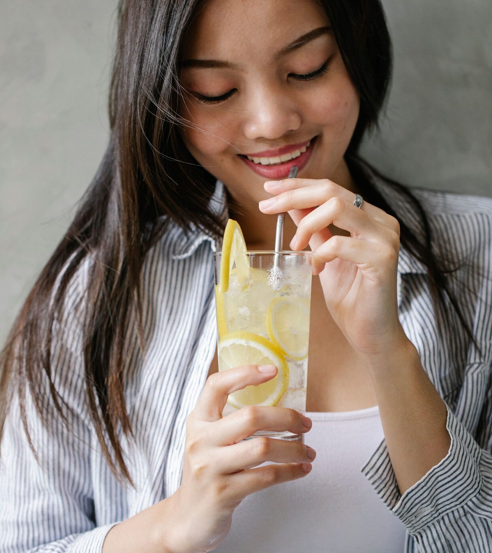 Femme asiatique qui boit un verre d'eau de coco citron