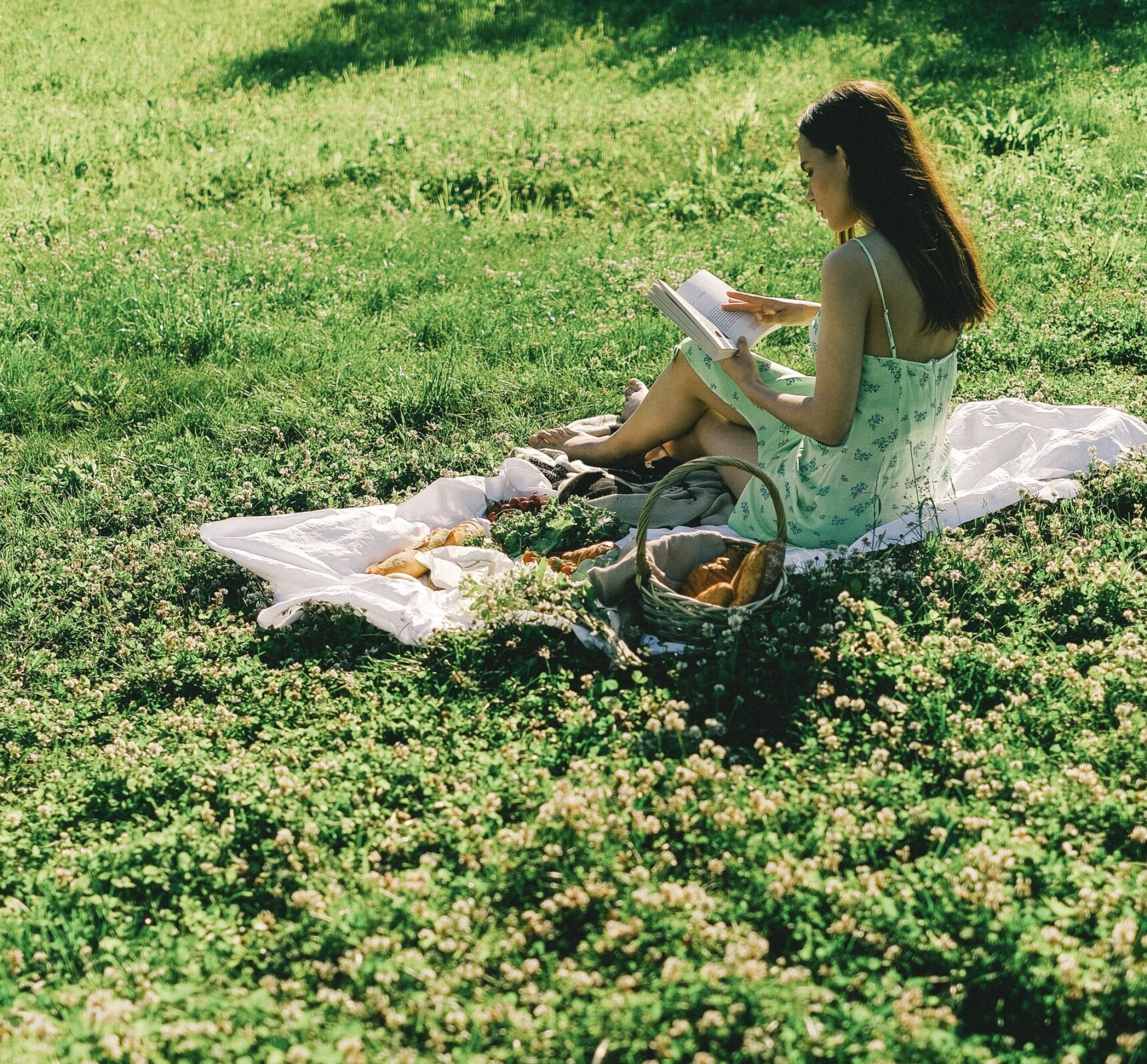 Une femme blanche brune lisant un livre sur l'herbe