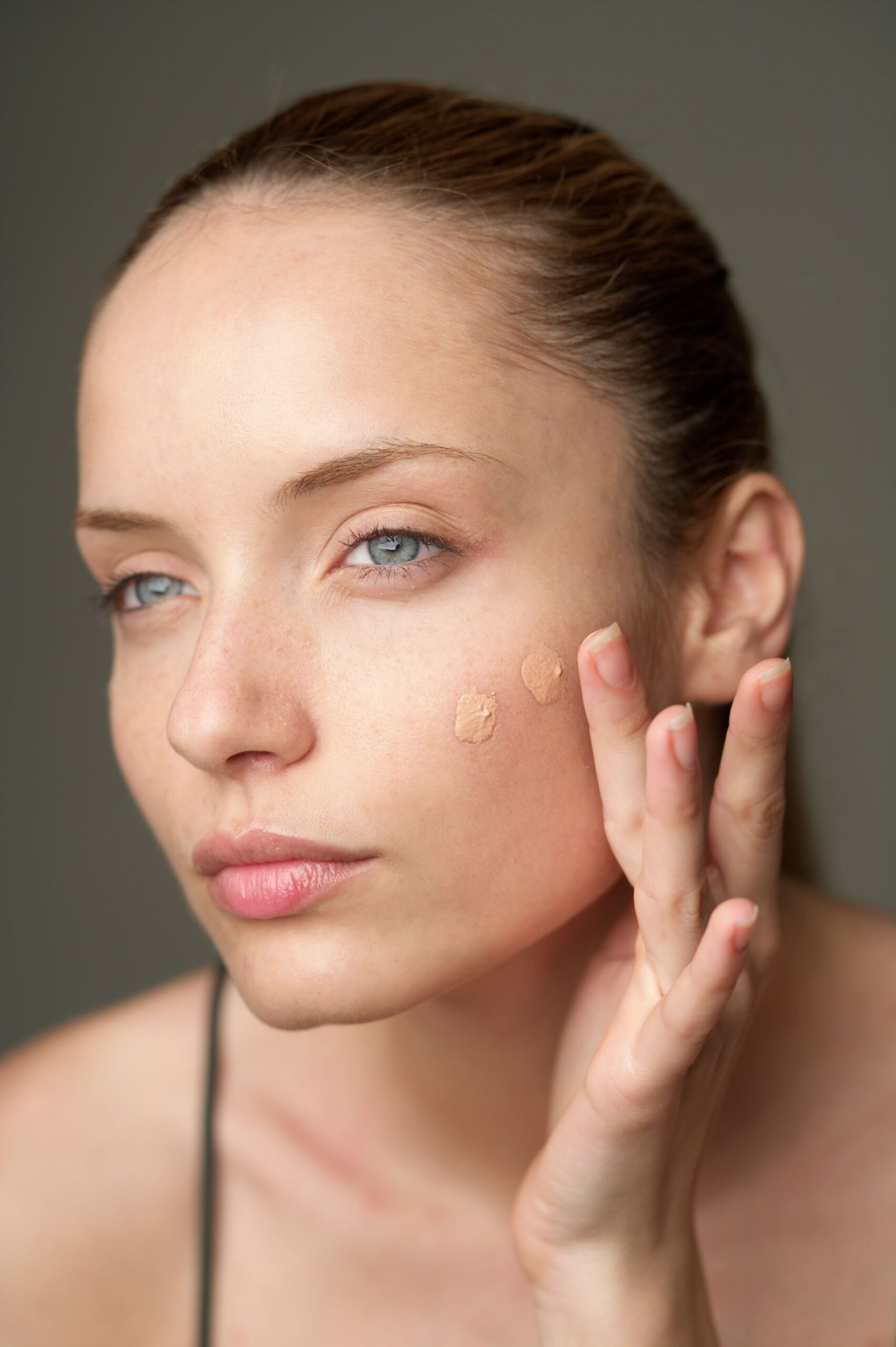Femme blanche et brune appliquant du fond de teint sur son visage