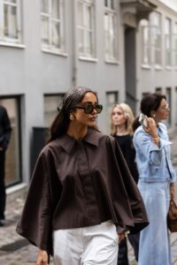 Femme blanche brune avec un foulard sur les cheveux et lunettes de soleil.