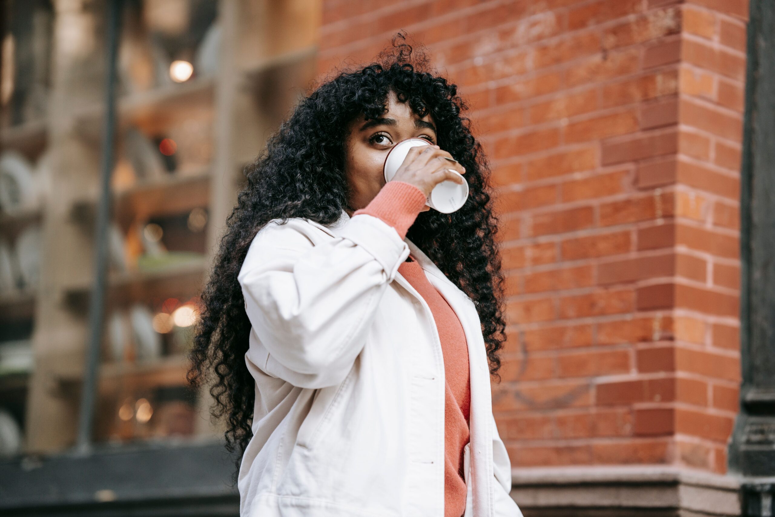 Femme noire cheveux bouclés buvant du café