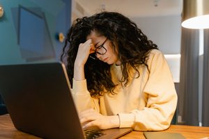 femme blanche aux cheveux bouclés fatiguée devant l'ordinateur