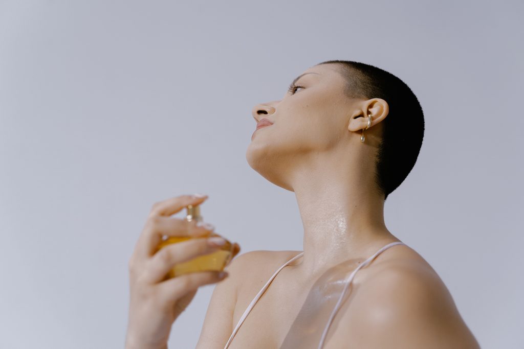 Femme blanche aux cheveux courts qui se met du parfum