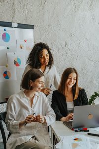trois femmes qui travaillent ensemble en souriant