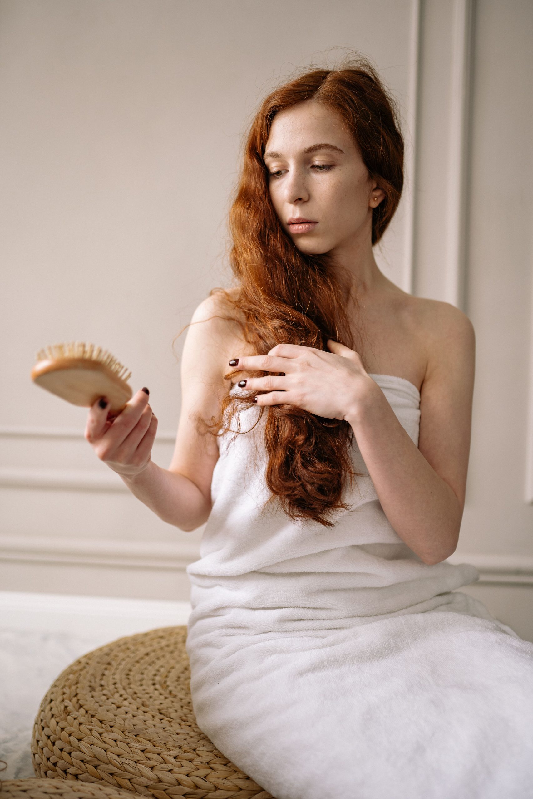 Femme blanche rousse perdant ses cheveux en se coiffant