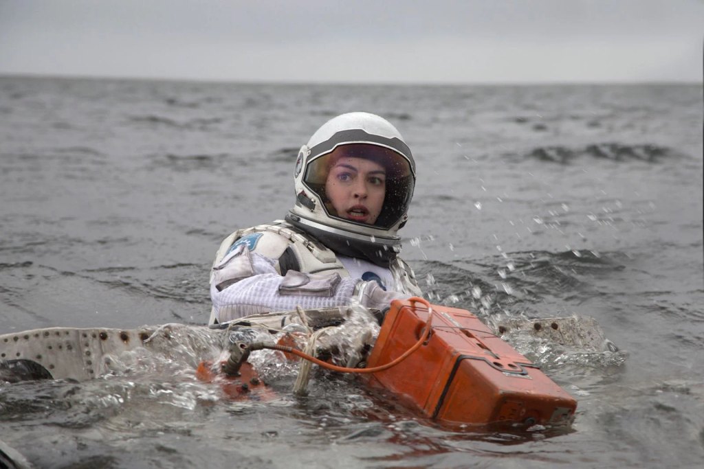 Scène du film Interstellar montrant Anne Hathaway dans l’eau, vêtue d’une combinaison de cosmonaute.