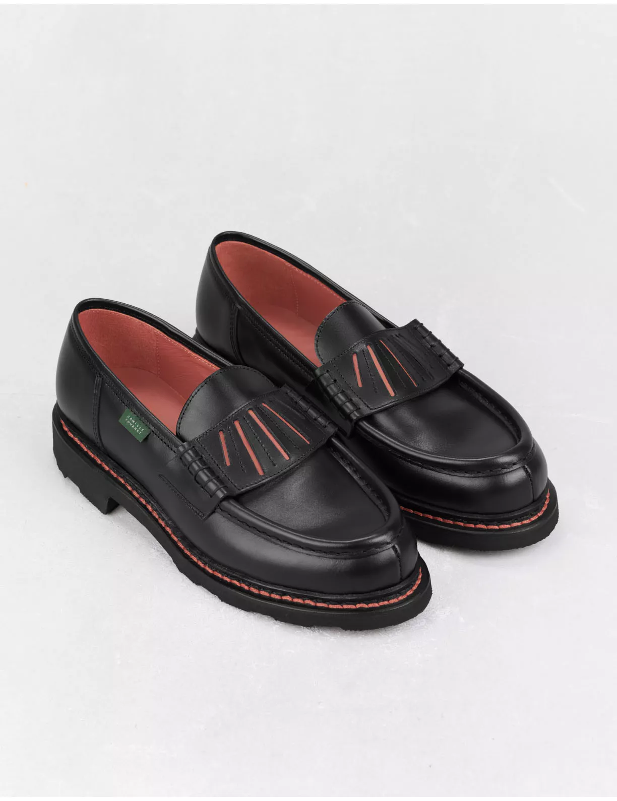 Mocassins en cuir noir avec des surpiqûres rouges.