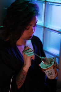 femme asiatique qui manche une glace près de son frigo