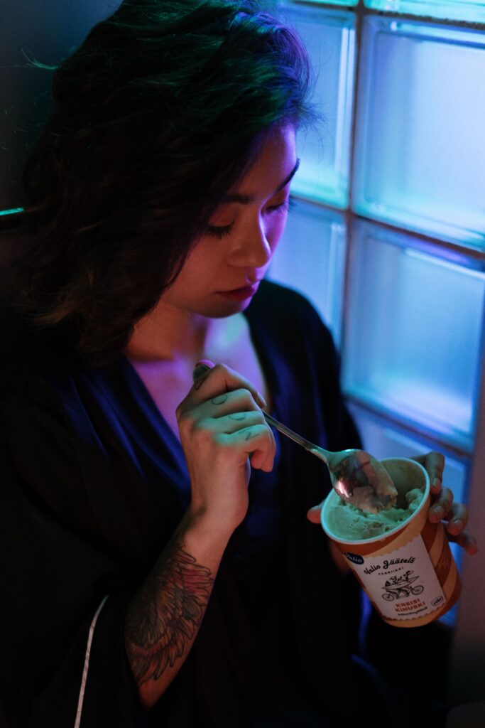 femme asiatique qui manche une glace près de son frigo
