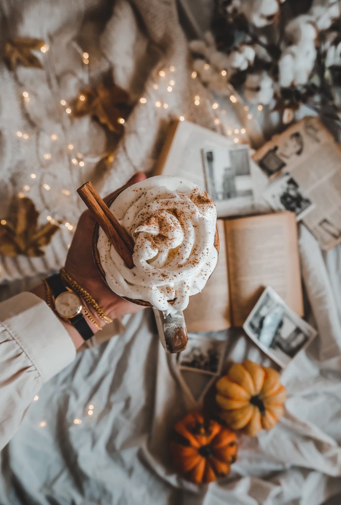 Main de femme tenant un chai latte en automne