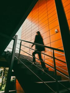 Une scène dynamique montrant une femme en mouvement dans un escalier contemporain aux murs d'un orange éclatant.