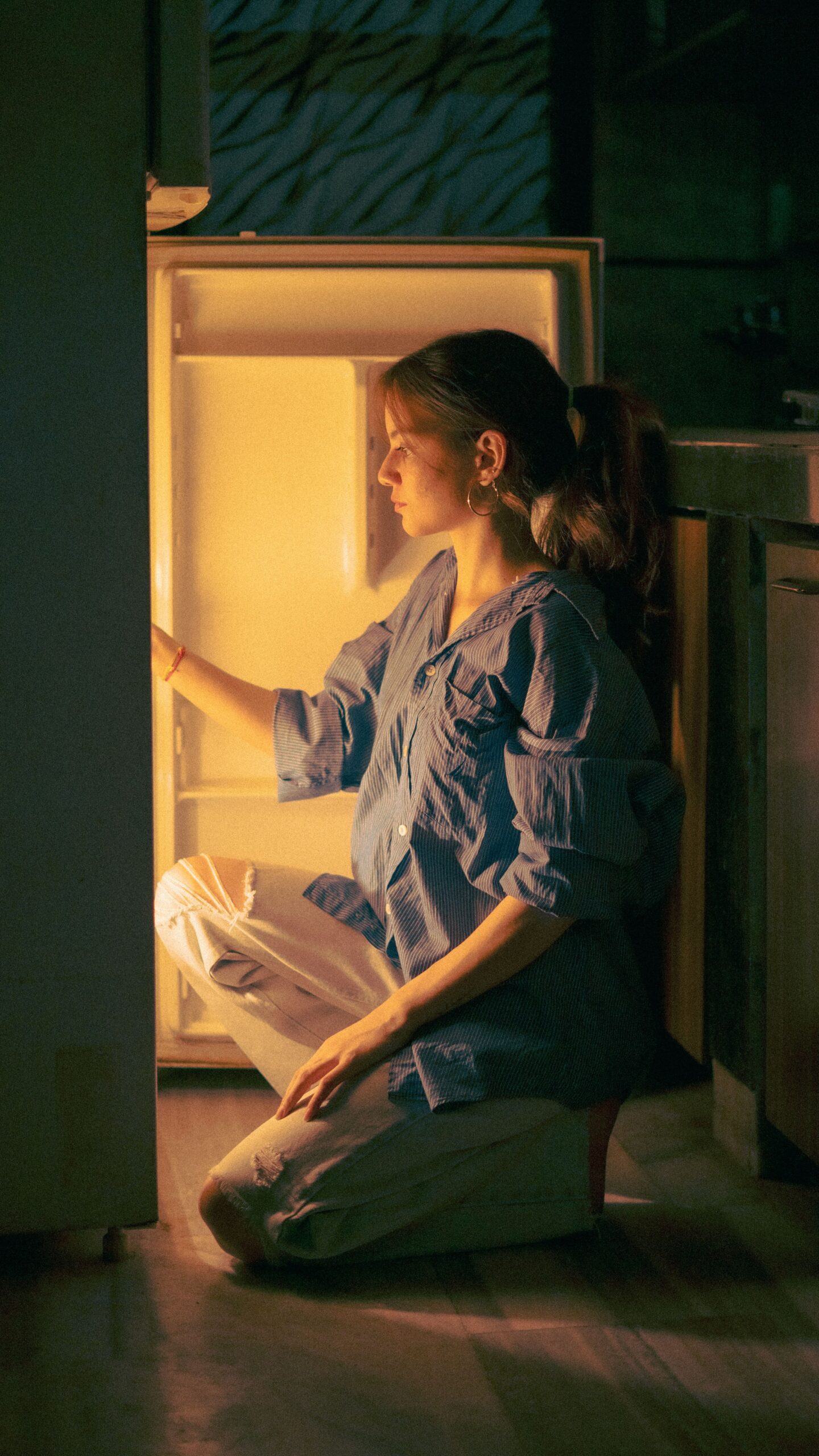 femme blanche près de son frigo le soir